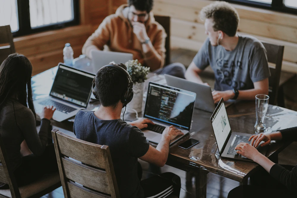 Engineers collaborating around a shared table of laptops